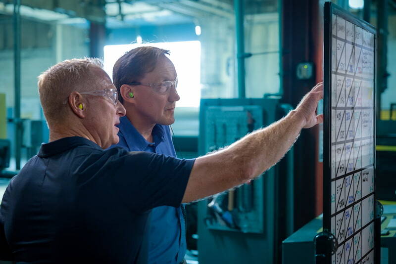 NCC steel drum supplier management team pointing to a board