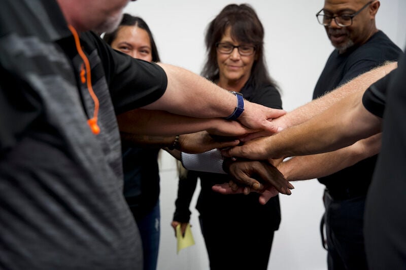 A team of employees stacking hands in a circle representing camaraderie