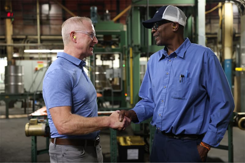 NCC employee shaking hands with customer at steel drum manufacturing facility