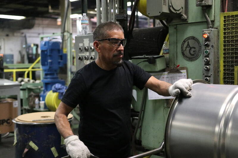 Worker inspecting steel drum for quality control at NCC’s manufacturing facility